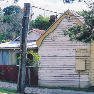 Side view, prior to re-construction, with enclosed skillion addition obscuring the rear enclosure
